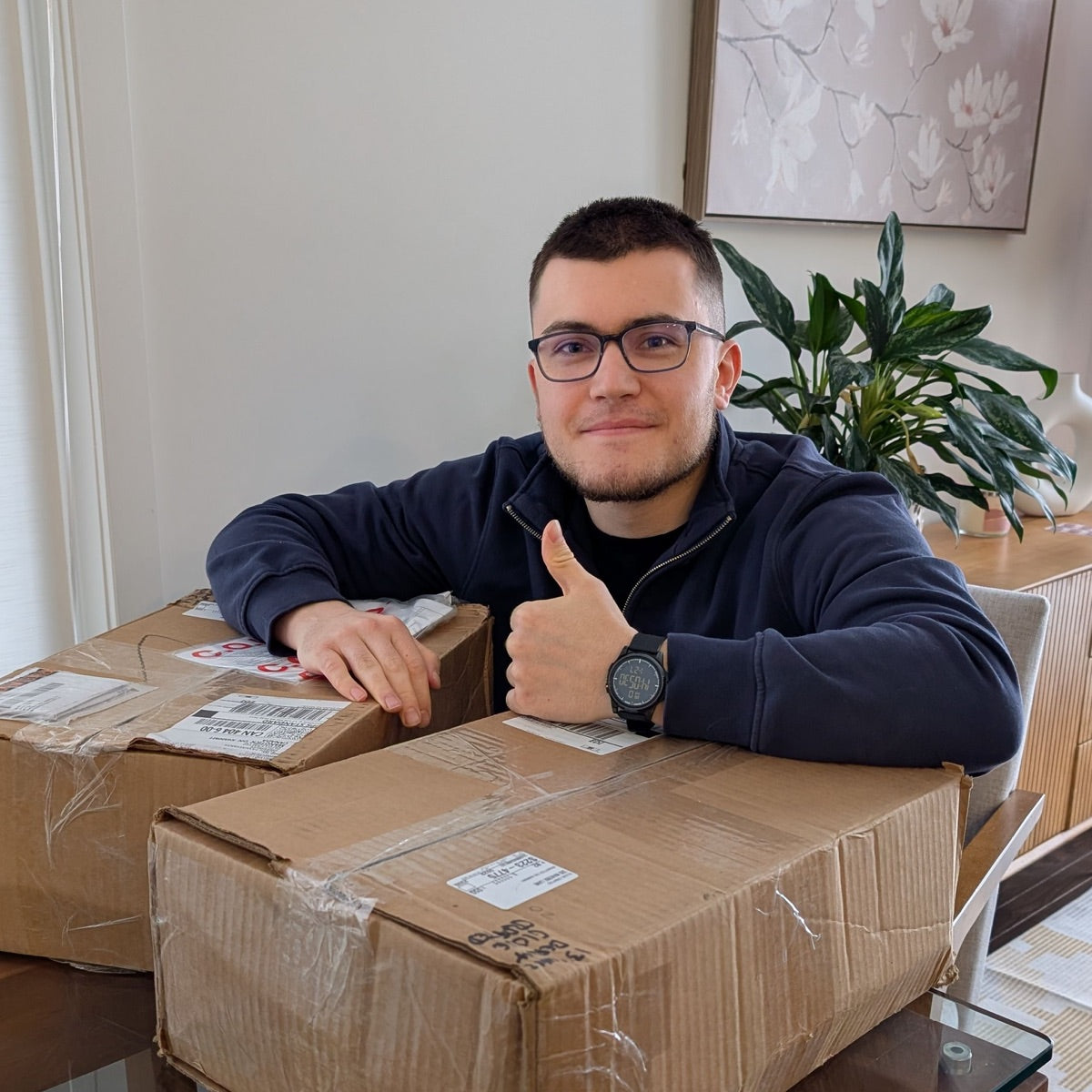 Ruben, founder of Glove Crafted, giving a thumbs up behind two shipping boxes